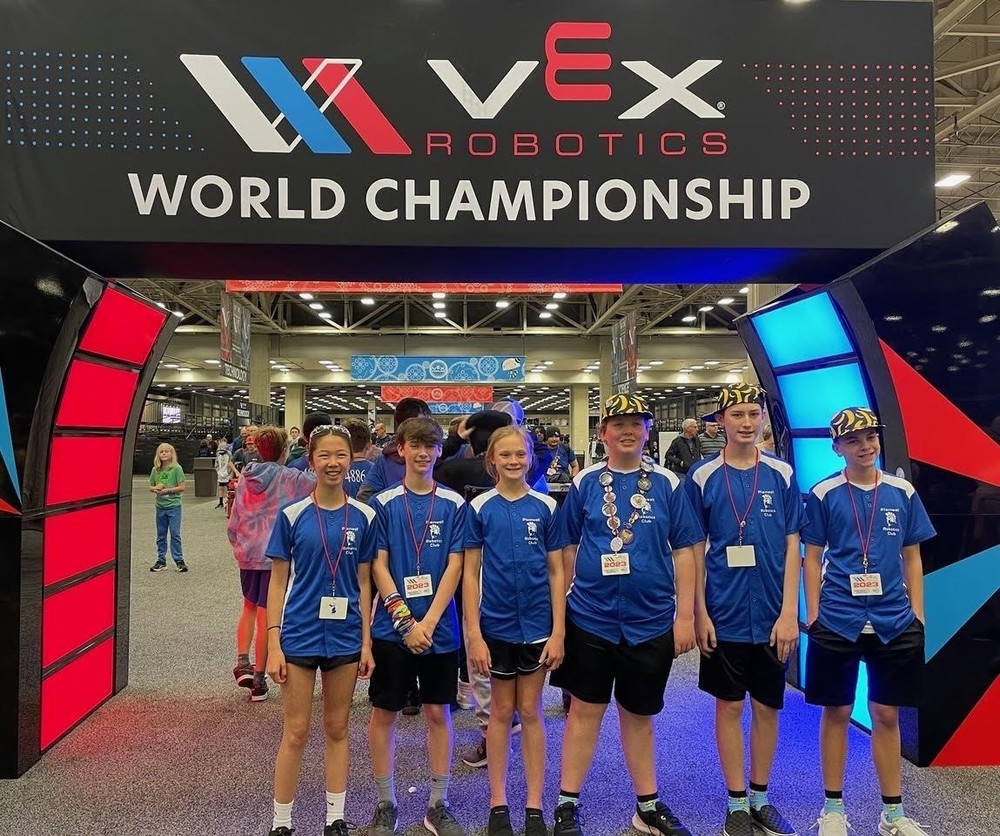 Students posing in front of VEX banner